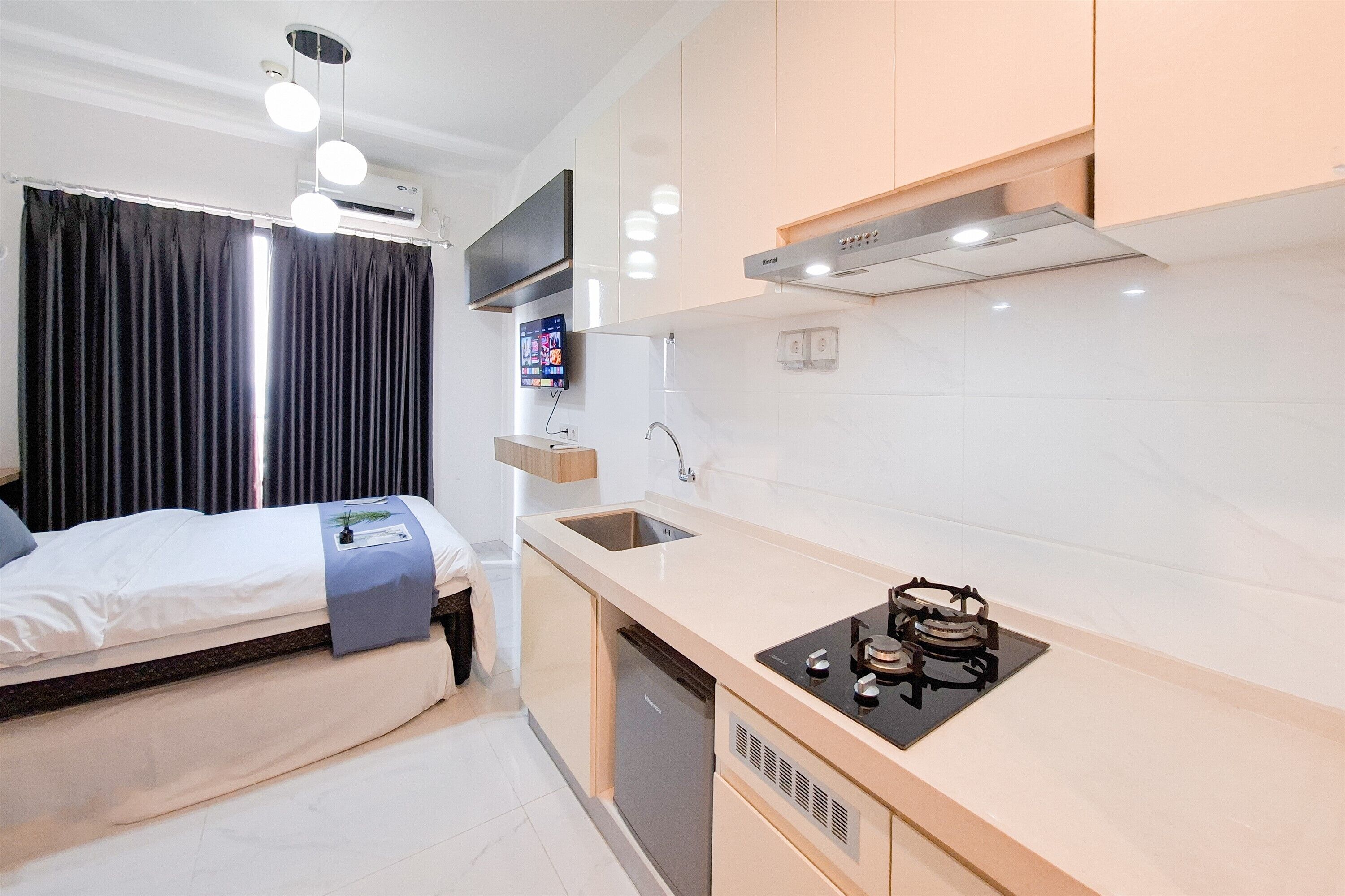 A compact kitchen with a built-in stove, a sink, and a modern pendant light.