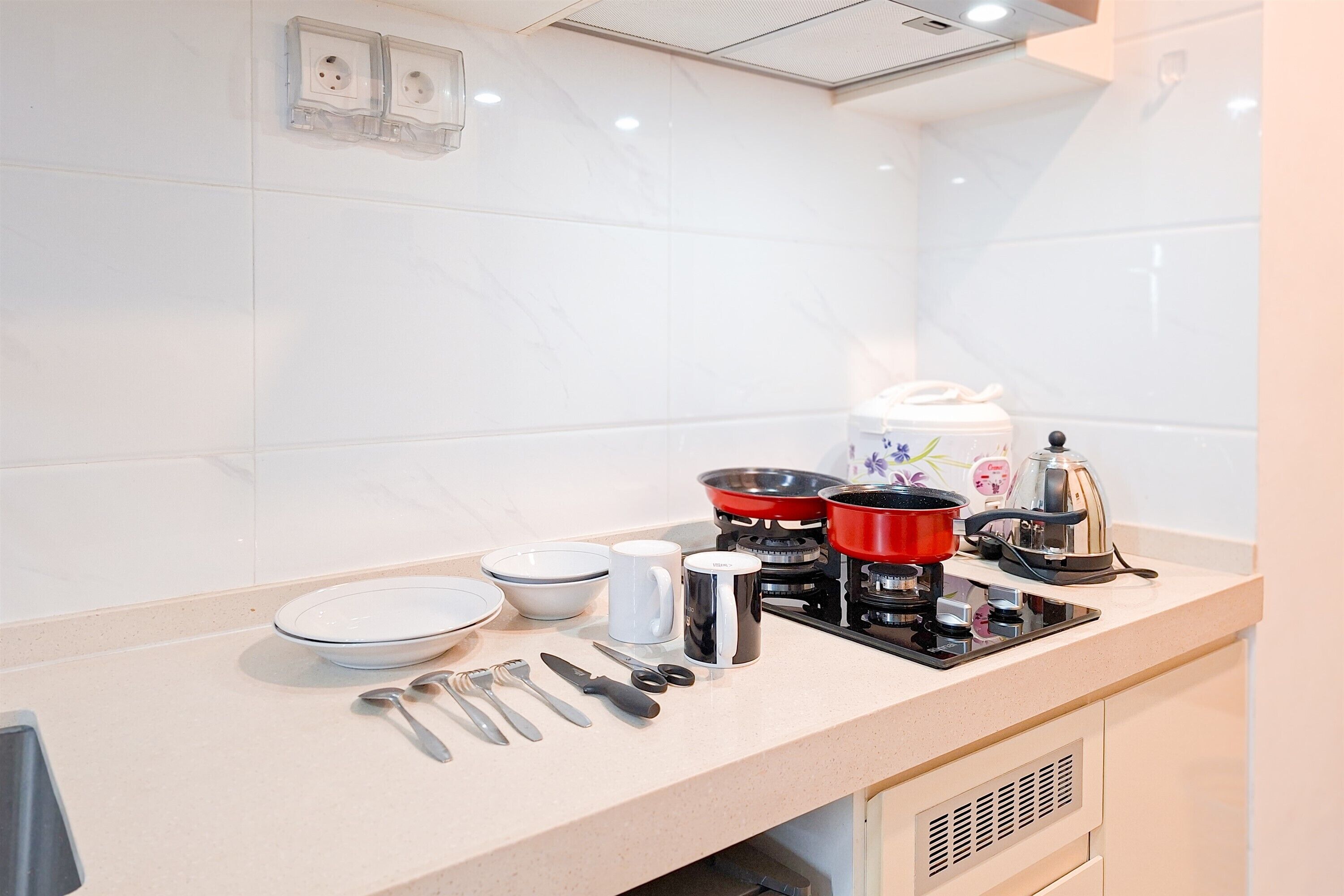 Une cuisine avec des carreaux de marbre blanc, une cuisinière à gaz, une machine à café et divers ustensiles de cuisine.