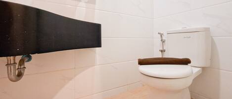 A bathroom with a white toilet, a black sink, and a white tiled wall.