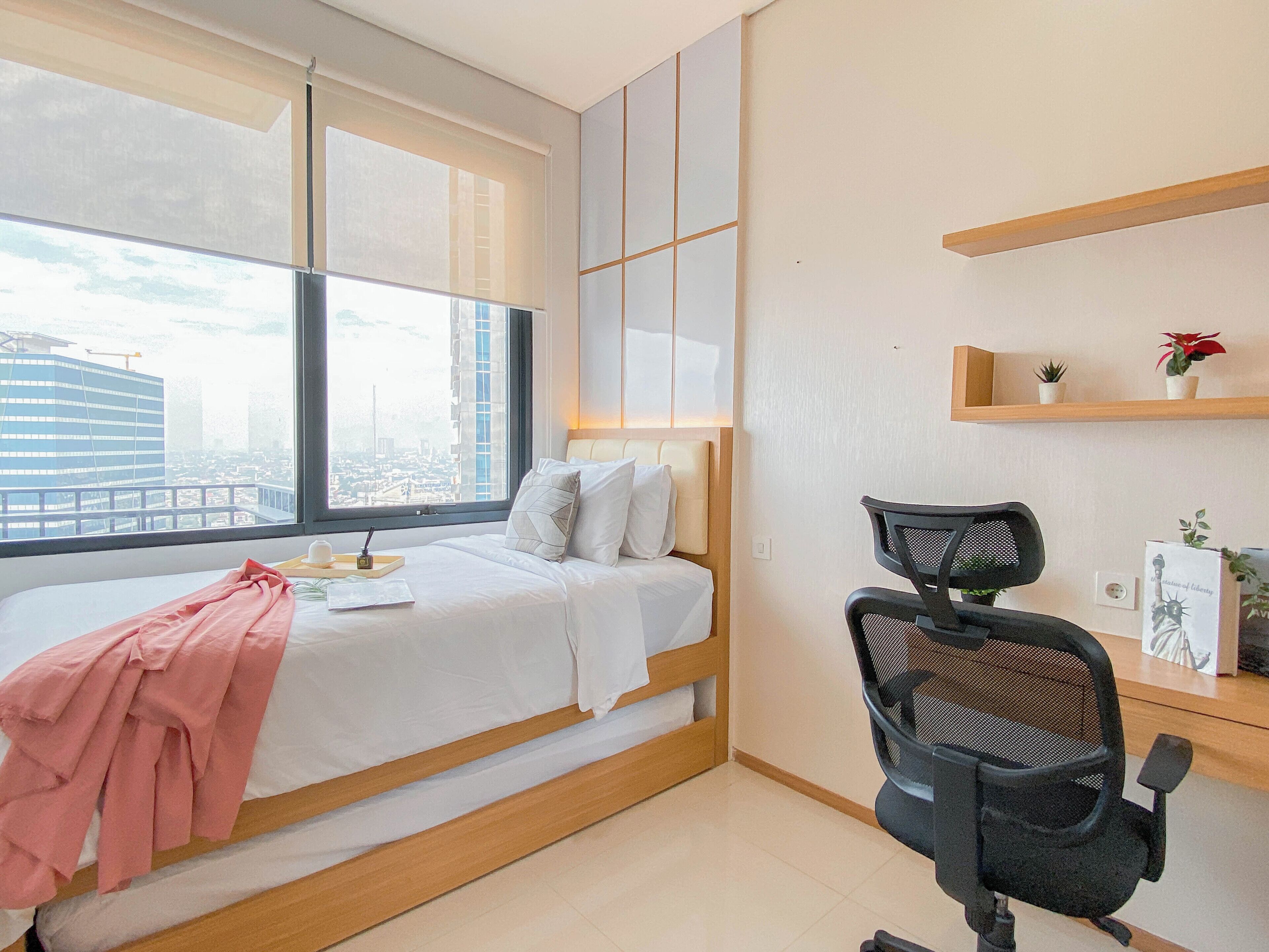 Een moderne hotelkamer met een bed, een bureau, een stoel en een raam met uitzicht op de stad.
