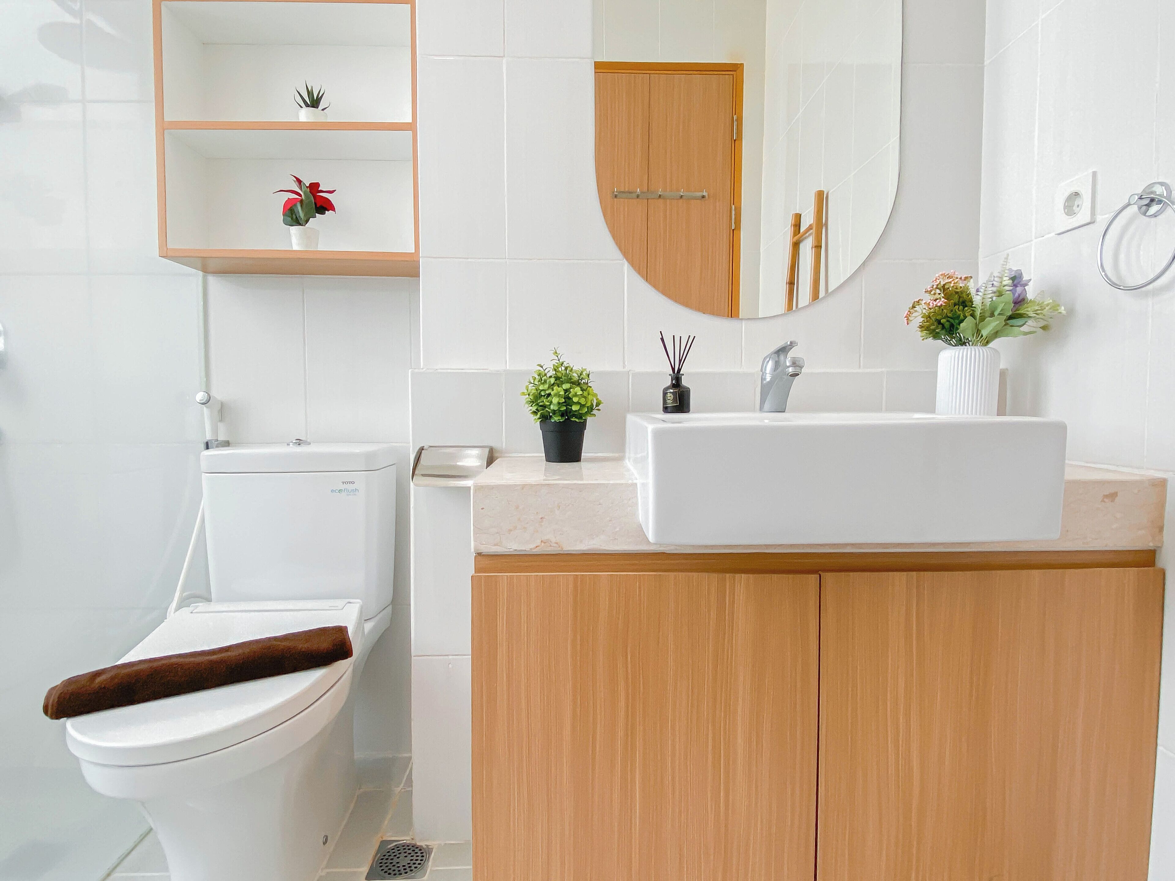Ein Badezimmer mit Toilette, Waschbecken, Spiegel und einem Regal mit Pflanzen.