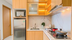 A modern kitchen with wooden cabinets, a stainless steel refrigerator, a sink, and a stove. - Warm Contemporary 2Br Apartment At Samara Suites (Jakarta)
