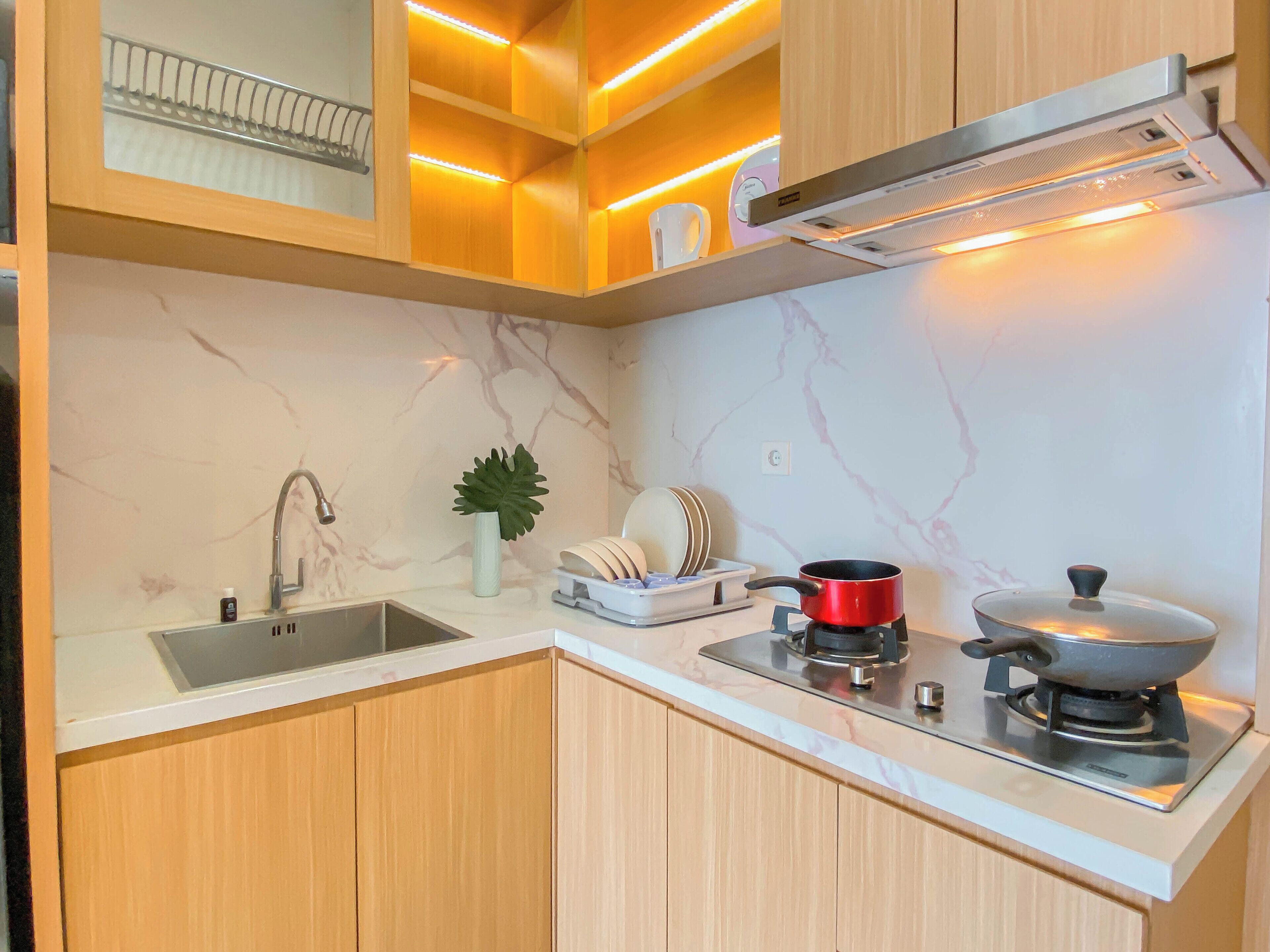 A modern kitchen with a marble backsplash, wooden cabinets, a stainless steel sink, and a gas stove.