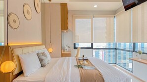 A modern bedroom with a large bed, bedside tables, a TV, and a balcony with a city view. - Warm Contemporary 2Br Apartment At Samara Suites (Jakarta)