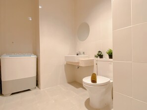 A bathroom with a toilet, sink, and a washing machine. - Modern Monochromatic 2Br Near Lrt Station At Apartment Samara Suites (Jakarta)