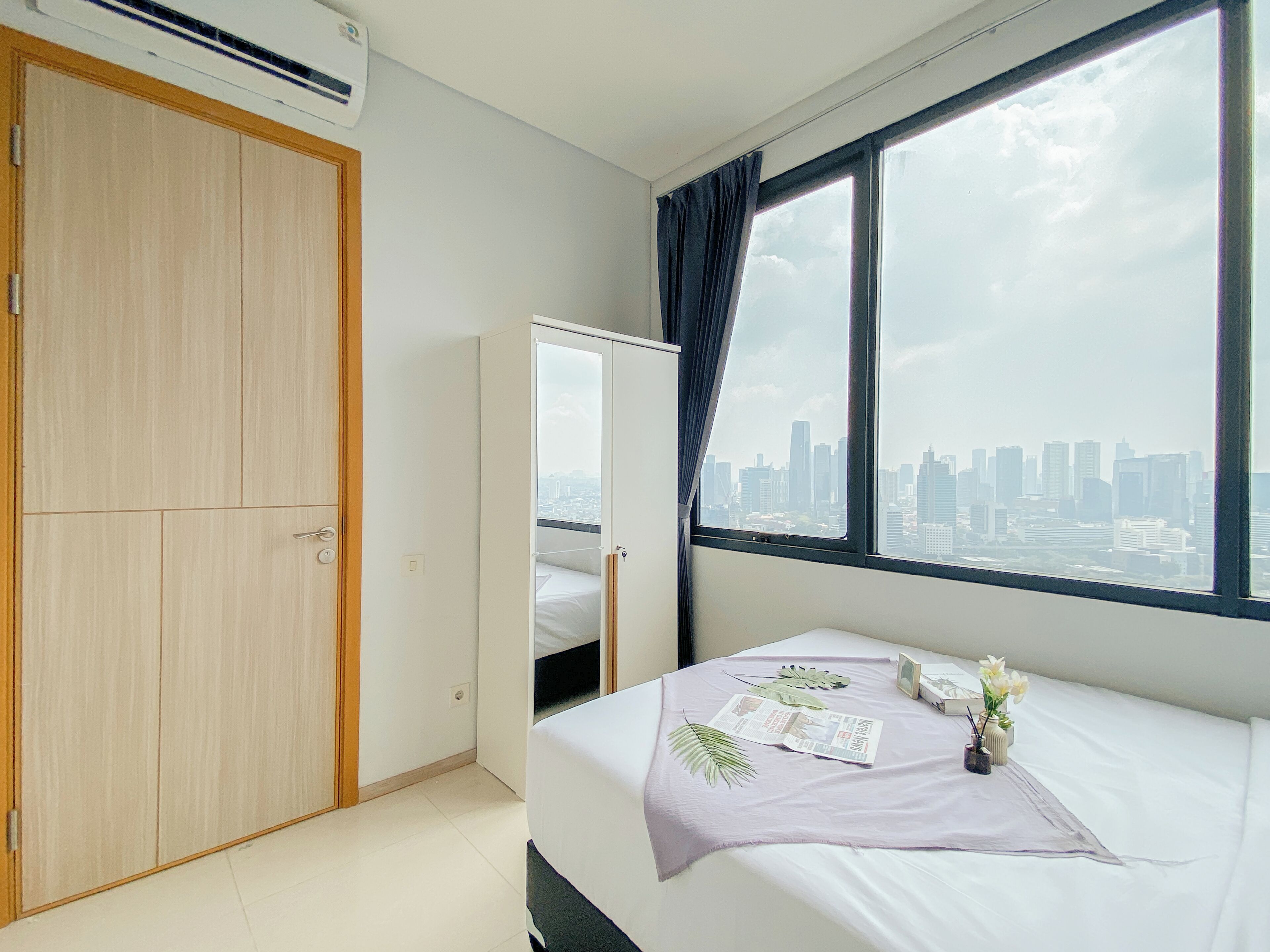 Una camera d'albergo con un letto, un armadio, una finestra vista città e un condizionatore d'aria.
