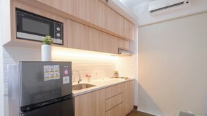 A modern kitchen with wooden cabinets, a stainless steel refrigerator, a microwave, and a sink. - Cozy And Spacious 1Br Apartment At Marina Ancol (Jakarta)
