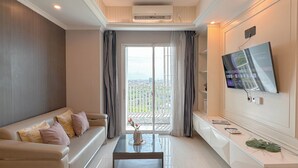 A modern living room with a sofa, coffee table, and a TV mounted on the wall. - Cozy And Spacious 1Br At Grand Sungkono Lagoon Apartment (Surabaya)