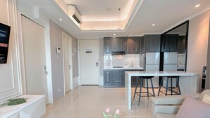 A modern kitchen with grey cabinets, a marble countertop, and a built-in stove. - Cozy And Spacious 1Br At Grand Sungkono Lagoon Apartment (Surabaya)