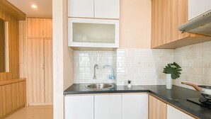 A modern kitchen with white cabinets, a stainless steel sink, and a black countertop. - Simple And Homey 2Br At Grand Kamala Lagoon Apartment (Bekasi)