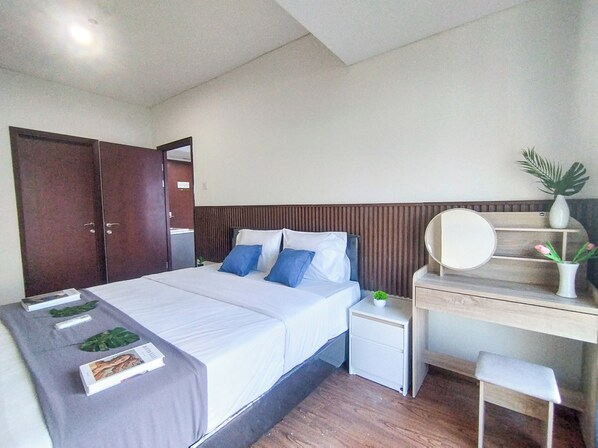 A bedroom with a bed, bedside table, nightstand, and a desk with a chair.
