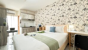 Egy modern hálószoba, amelyben egy nagy ágy, egy éjjeliszemélyzet, egy szék található, és kilátás nyílik a konyhára.
