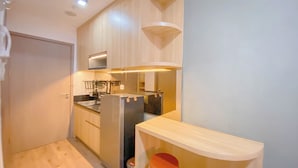 Une cuisine compacte avec des meubles en bois, un four encastré et un coin bar avec des tabourets.
