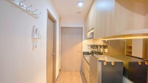 Un couloir étroit mène à une cuisine équipée d’appareils modernes et dotée d’un plancher en bois.