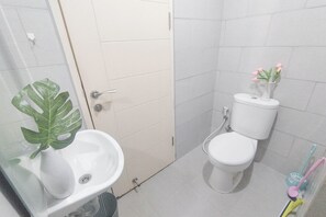 Een badkamer met een wit wastafelmeubel, toilet en een douchecabine van glas.