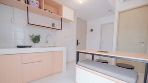 A modern kitchen with light wood cabinets, a white countertop, and a built-in bench with a cushioned seat. - Cozy And Spacious 2Br Apartment Tokyo Riverside Pik 2 (Teluknaga)