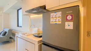 Een moderne keuken met een inbouwkoelkast, een raam en een grijze bank.