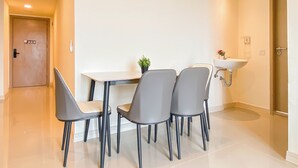 Een moderne eetruimte met een tafel, vier stoelen, een kleine potplant en een wastafel aan de muur.