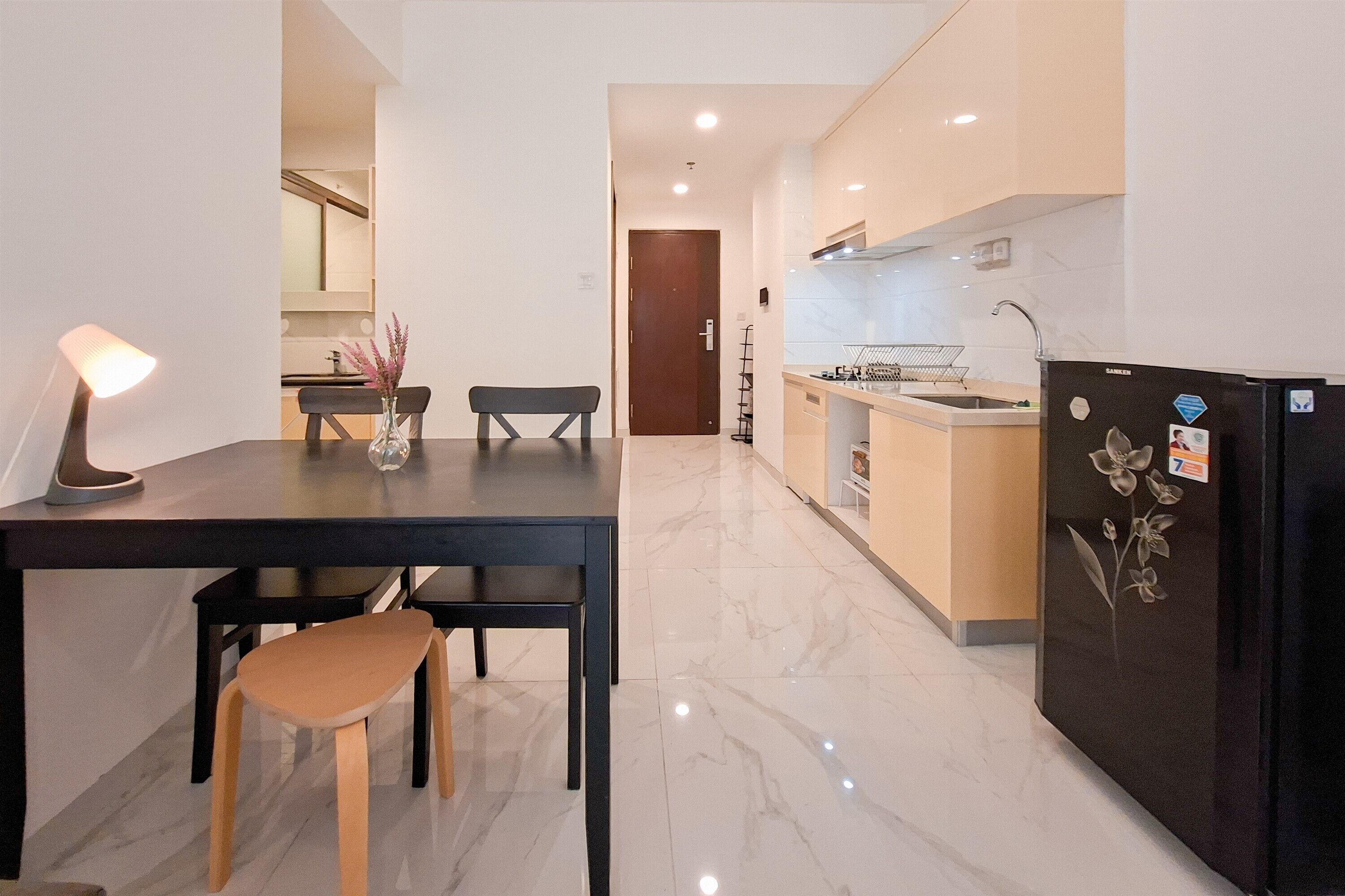 A modern kitchen with a black refrigerator, a dining table with chairs, and a small island with a sink.