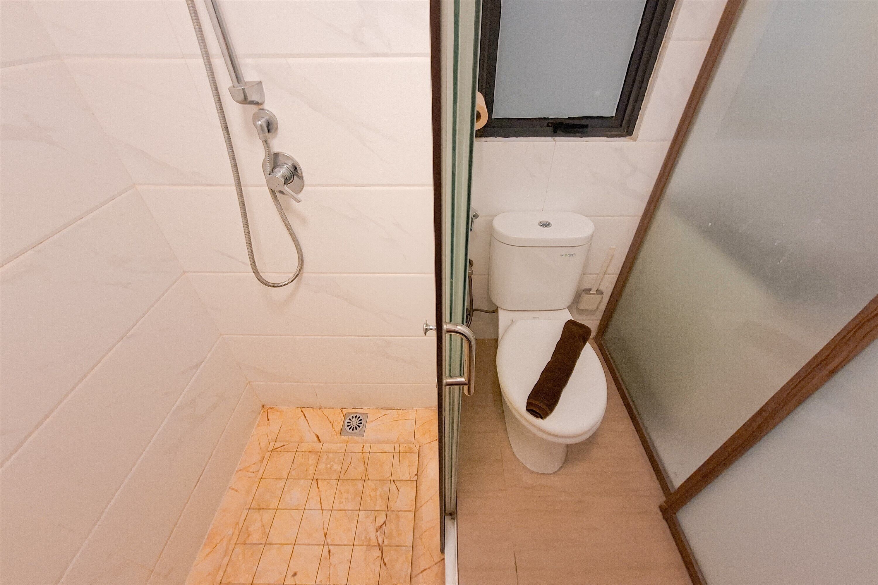 Een badkamer met een douche, toilet en een houten vloer.