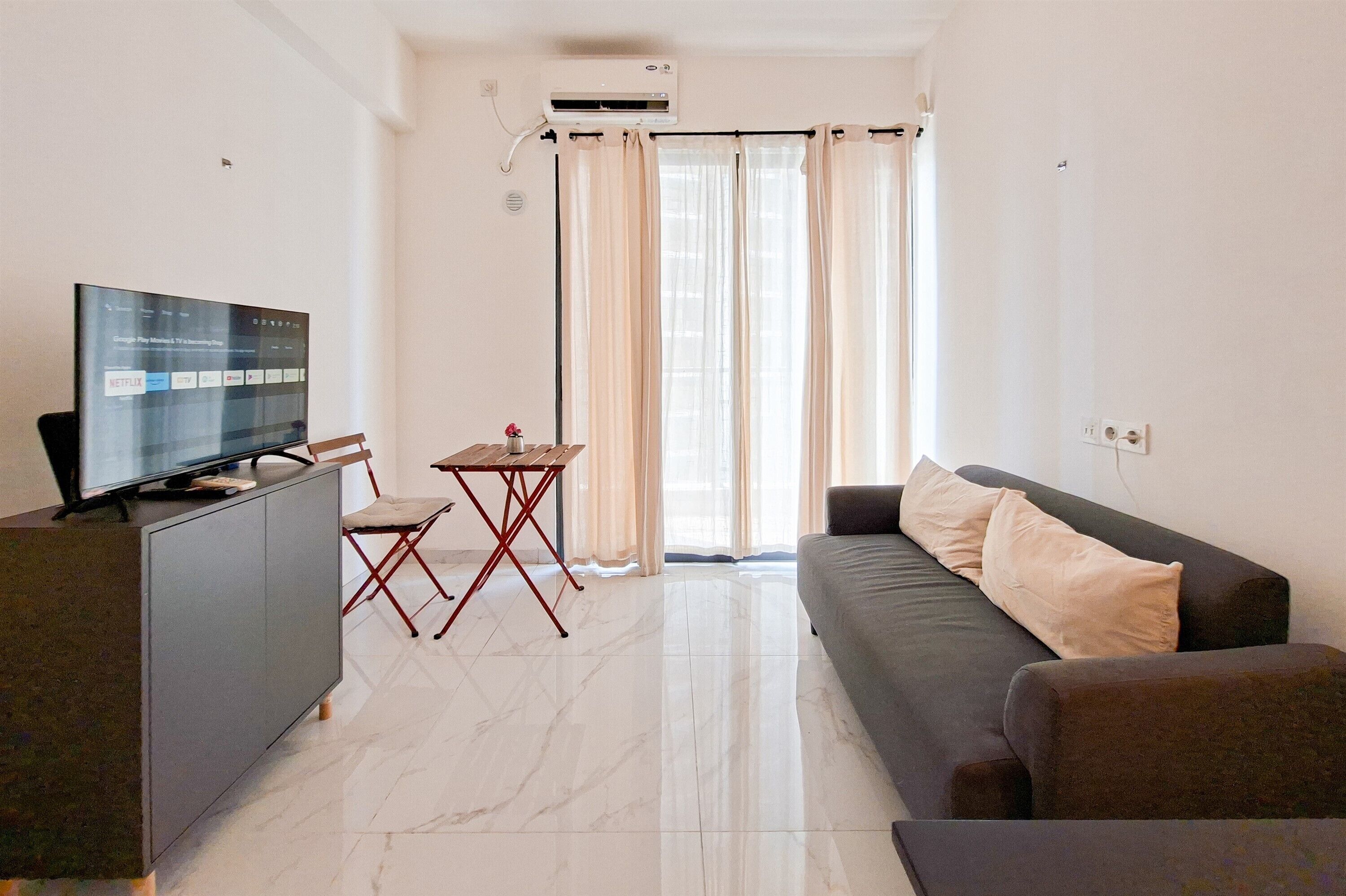 Un salon moderne avec un téléviseur à écran plat, un canapé, une table à manger et une chaise.