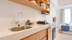 Una cocina moderna con baldosas blancas, armarios de madera, un lavamanos de acero inoxidable y una estufa empotrada.