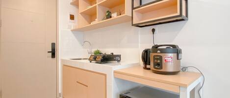 A compact kitchen with a built-in dishwasher, a coffee maker, and a rice cooker on the countertop.