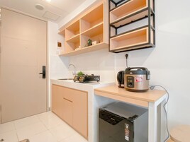 Uma cozinha compacta com lava-louças embutida, cafeteira e cozedor de arroz na bancada.