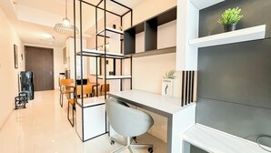 Una cocina moderna con una isla central, una zona de comedor con sillas de madera y un escritorio empotrado con silla.