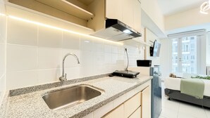 A modern kitchen with a stainless steel sink, granite countertop, and a black range hood.