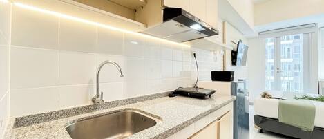 A modern kitchen with a stainless steel sink, granite countertop, and a black range hood.