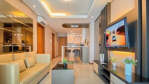 A modern living room with a sofa, a coffee table, and a TV mounted on the wall. - Modern And Spacious 2Br Apartment Green Bay Condominium (Jakarta)