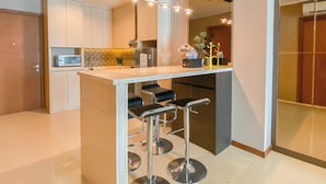 A modern kitchen with a central island, bar stools, and a microwave. - Modern And Spacious 2Br Apartment Green Bay Condominium (Jakarta)