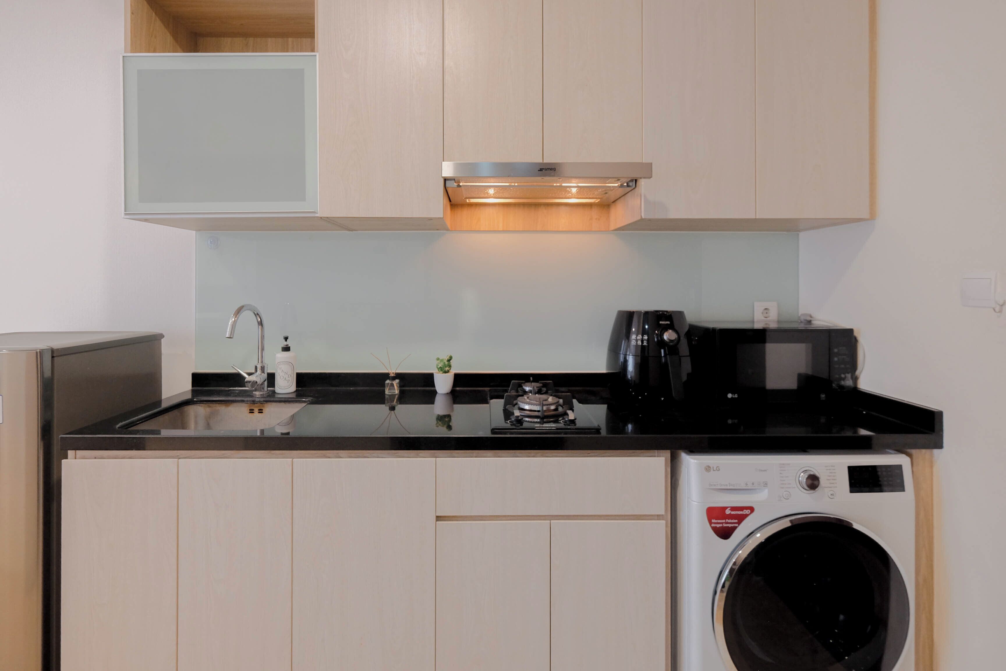 Een kleine keuken met een wasmachine, een koffiezetapparaat en een spoelbak.