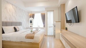 Une chambre à coucher moderne avec un grand lit, un téléviseur fixé au mur et une coiffeuse en bois.