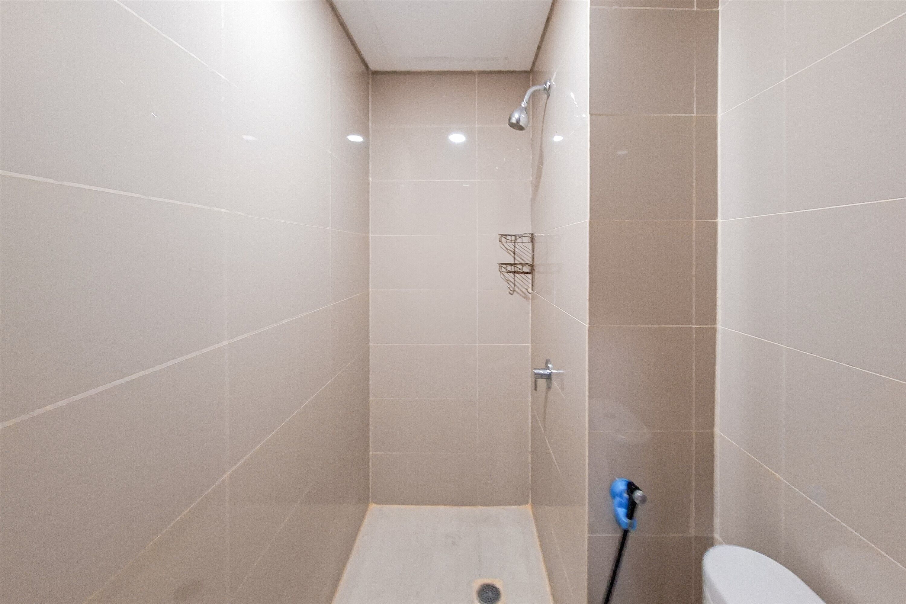A small, enclosed shower area with a showerhead, a towel rack, and a toilet.