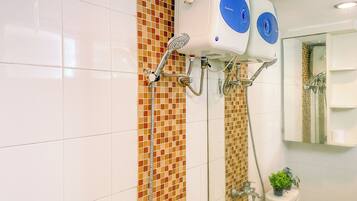 A bathroom with a shower, a toilet, and a mirror.