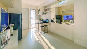 A modern kitchen with a dining area, a TV, and a refrigerator. - 2Br Space Near Mall At Bassura City Apartment (Jakarta)
