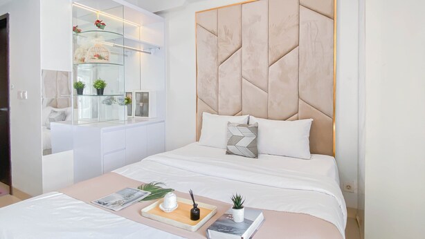 Une chambre moderne avec un grand lit, une table de chevet, une armoire intégrée et une coiffeuse avec des étagères et une façade en verre.