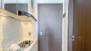 Une cuisine compacte équipée d’un lave-vaisselle, d’une cuisinière et d’une porte dotée d’une poignée.