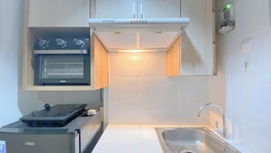 Une cuisine compacte équipée d’un four encastré, d’un réfrigérateur et d’un évier.
