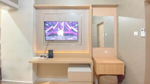 Une chambre moderne avec un grand téléviseur fixé au mur en bois, un petit bureau avec une chaise et un miroir au-dessus du bureau.