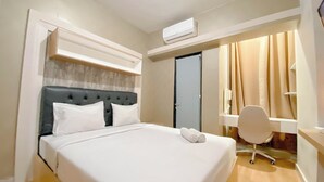 Un lit bien fait, avec des draps blancs, une tête de lit capitonnée et une serviette enroulée posée sur le côté.