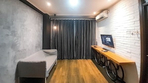 A small, modern room with a single bed, a desk with a computer, and a bicycle rack.