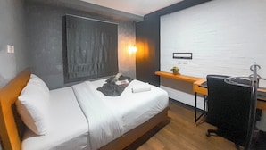 A small, modern room with a bed, a desk, and a chair.