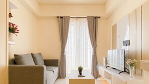 A modern living room with a sofa, a coffee table, a TV, and a window with curtains.