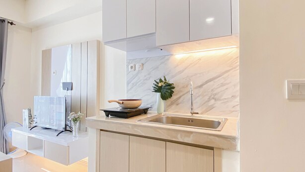 A modern kitchen with a built-in stove, a sink, and a marble backsplash.