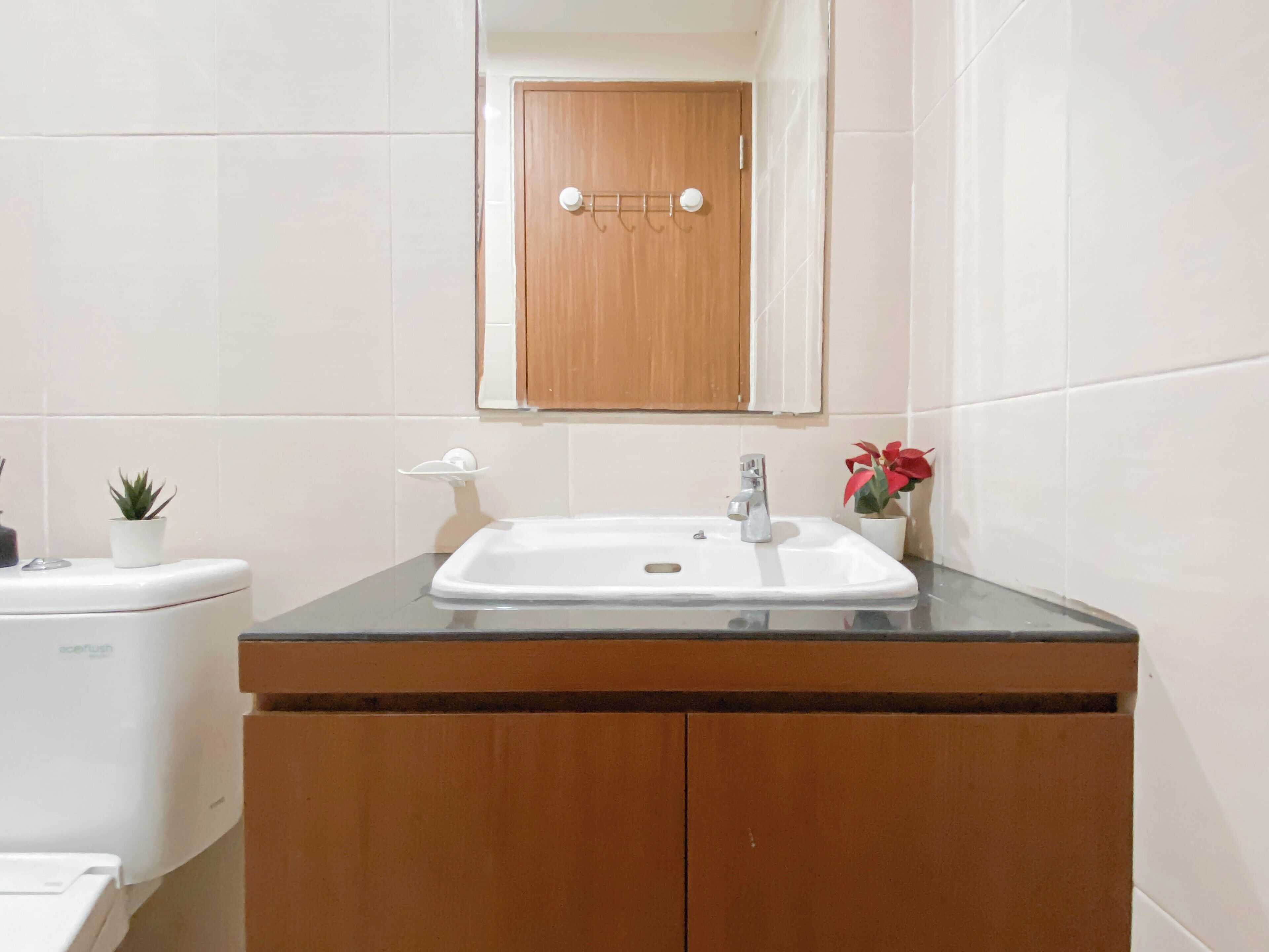 A bathroom with a white sink, wooden cabinets, a mirror, and a toilet.