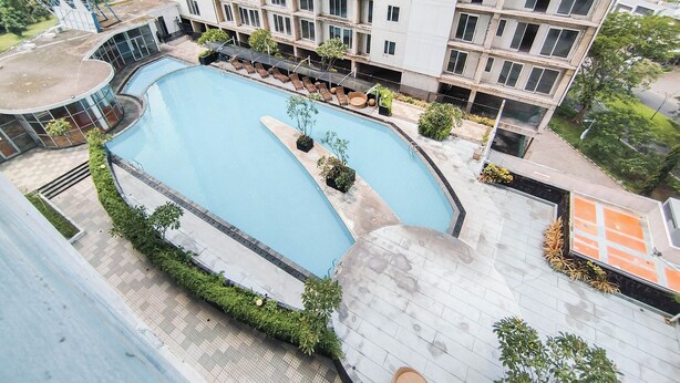 A modern building with a rooftop pool, surrounded by greenery and a paved walkway. - Minimalist Studio (No Kitchen) At Tamansari Prospero Sidoarjo Apartment (Sidoarjo)
