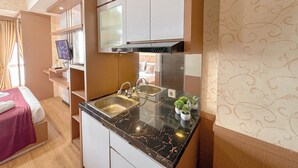 A compact kitchen with two sinks, a microwave, and a small countertop area with potted plants. - Minimalist Studio (No Kitchen) At Tamansari Prospero Sidoarjo Apartment (Sidoarjo)